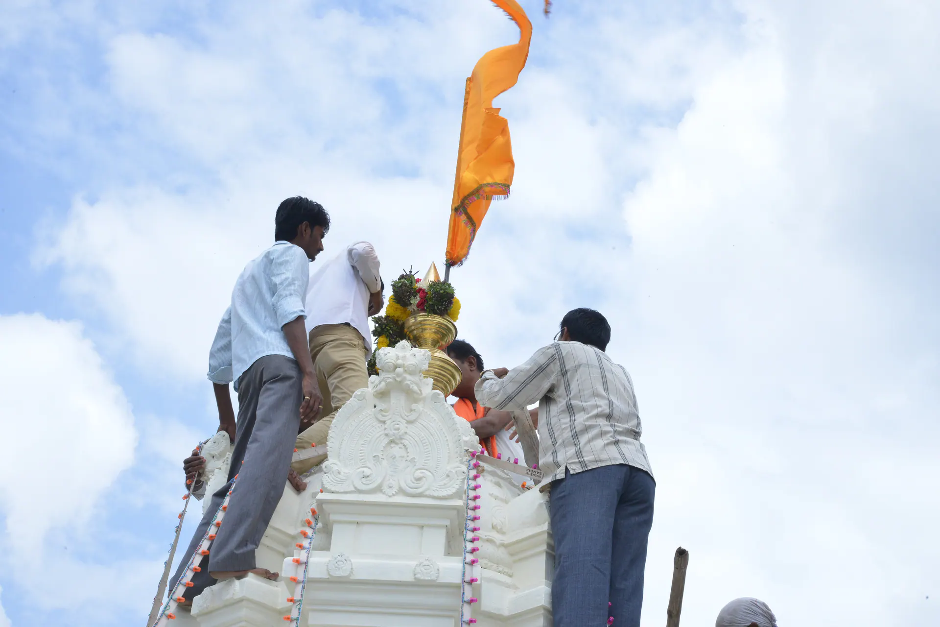 Devotees raising a saffron flag on the temple shikhara